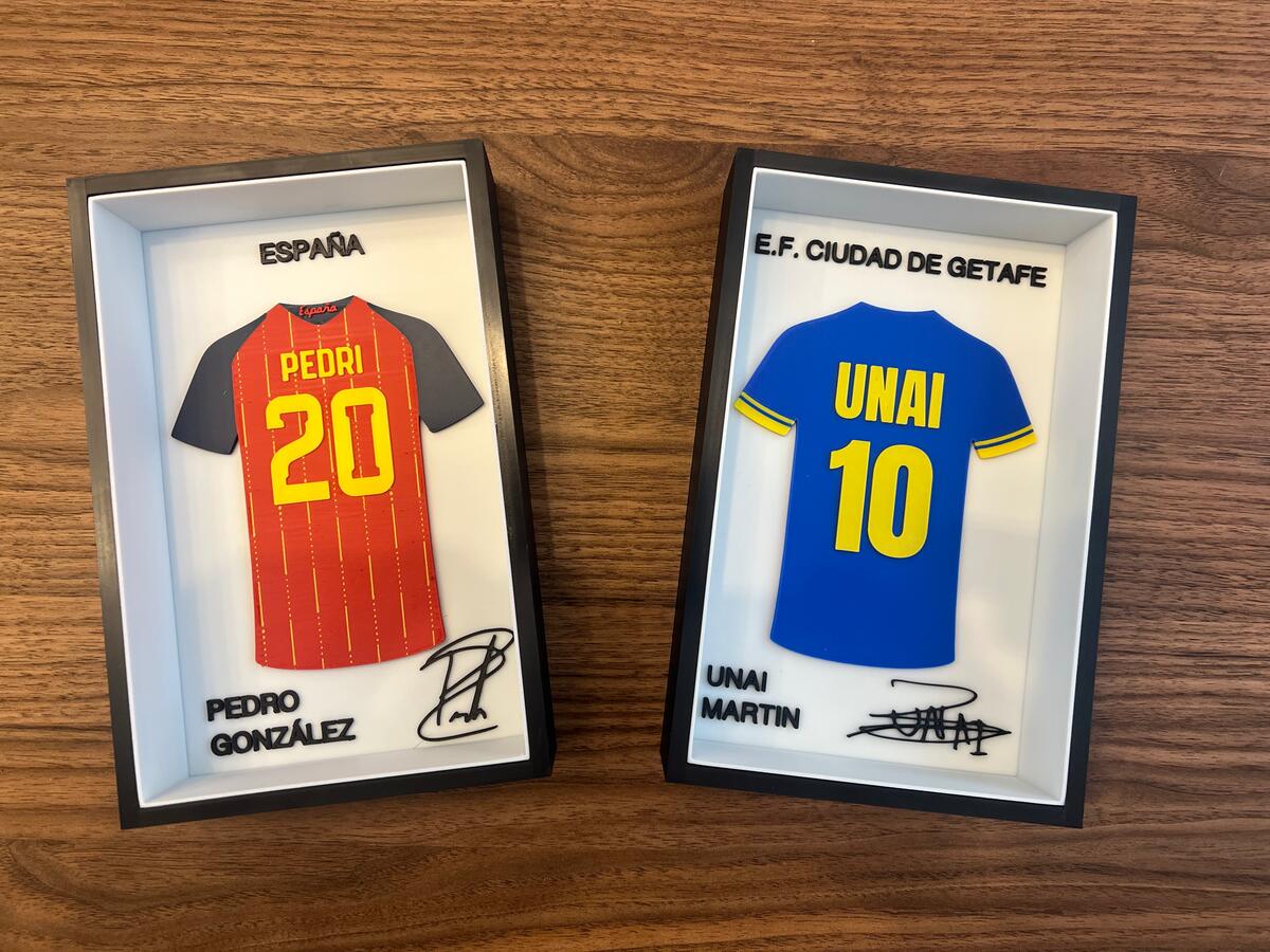 Dos cuadros con camisetas de fútbol impresas en 3D en relieve a color, cada una con su nombre, dorsal y firma, enmarcadas en negro